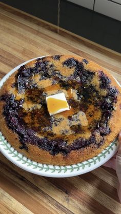 a blueberry cake with butter on top is sitting on a green and white plate