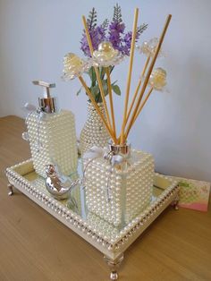 a tray with soap, lotion and flowers on it sitting on a wooden table