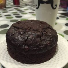 a chocolate cake sitting on top of a white plate next to a cup of coffee