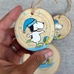 a hand holding a wooden ornament with a cartoon dog on it