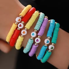 four different colored bracelets with hearts and eyes on each one hand, all stacked together