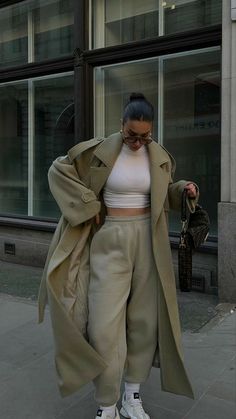 a woman is walking down the street in her pants and jacket, with one hand on her hip