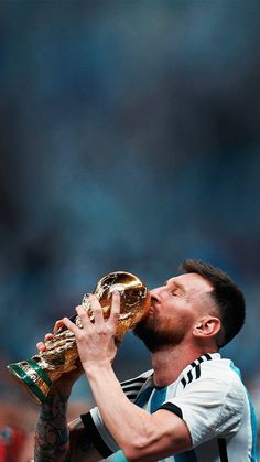 a man drinking from a golden trophy while holding it in his hand and looking up at the sky