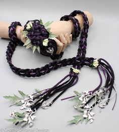 an assortment of jewelry is displayed on a white surface with green leaves and flowers in the center