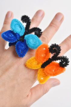 a hand with three small rings on it's fingers and one is wearing an orange, blue, and black ring