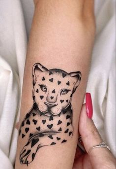 a woman's arm with a cheetah and hearts tattoo on the arm