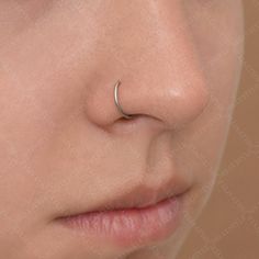 a woman's nose with a nose ring on her left side, and a nose piercing in the middle