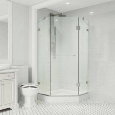 a white bathroom with a walk in shower next to a toilet and sink on a tiled floor