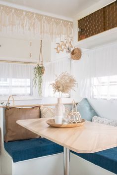 a table and bench in a small room with curtains on the window sill above it