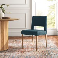 a blue chair sitting on top of a rug next to a table