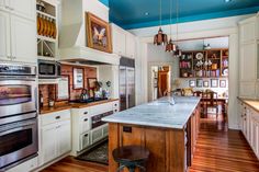 a kitchen with white cabinets and an island in front of the stove top ovens