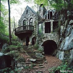 an old stone house in the woods with stairs leading up to it's entrance