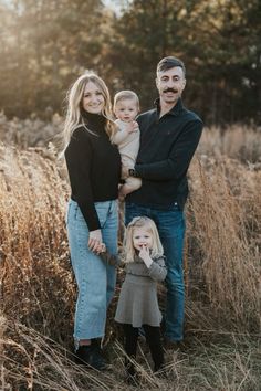 a man and woman with two children standing in tall grass