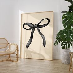 a black bow is hanging on the wall next to a chair and potted plant