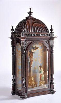 an ornate wooden clock with figurines in it's display case on a white background