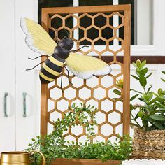 a yellow and black bee sitting on top of a planter next to a potted plant