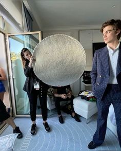 two people are standing in a room with one holding a large object up to the camera