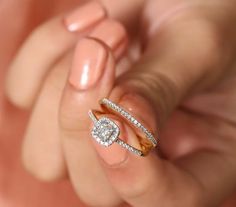 a woman's hand holding a diamond ring with two diamonds on top of it