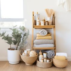 a shelf filled with lots of towels and other items next to a potted plant