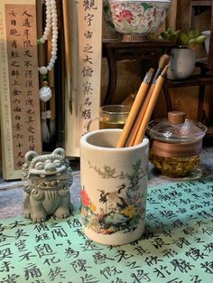 two pencils are sitting in a cup with writing on the table next to it