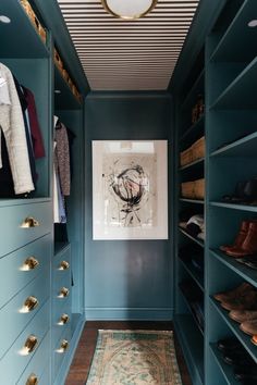 a walk in closet with blue painted walls and wooden flooring, an area rug on the floor