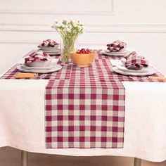 a red and white checkered table cloth on a dining room table with place settings