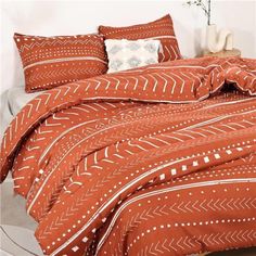 a bed with an orange comforter and pillows