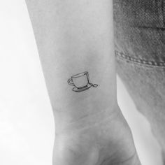 a black and white photo of a coffee cup tattoo on the left inner arm,