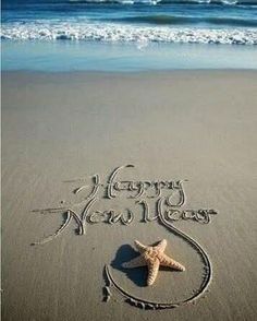 a happy new year written in the sand with a starfish on it's side