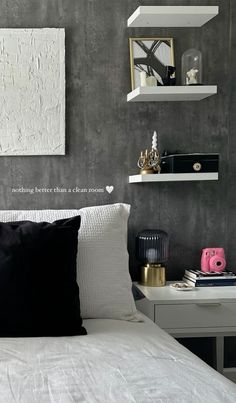 a white bed topped with pillows next to shelves