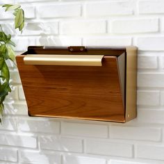 a wooden file cabinet hanging on a brick wall next to a potted green plant