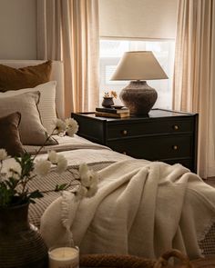 a bed with white flowers on it next to a night stand