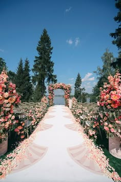 an outdoor wedding setup with flowers and greenery on the aisle, surrounded by tall trees