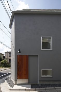 a grey house with a wooden door and window on the side of the building is shown