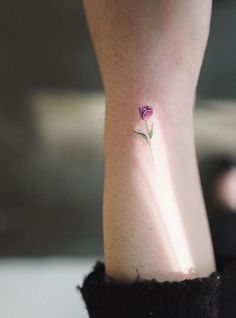 a small flower tattoo on the ankle is seen in this image, it appears to be purple