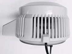 a white light fixture mounted on the side of a wall next to a black cord