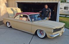 a man standing next to an old car in front of a garage