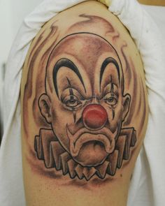 a close up of a person with a tattoo on their arm and shoulder, wearing a clown mask