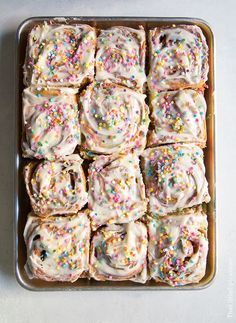 sprinkle covered doughnuts in a pan on a white table top, ready to be eaten