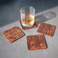 four wooden coasters sitting on top of a table next to a glass filled with liquid