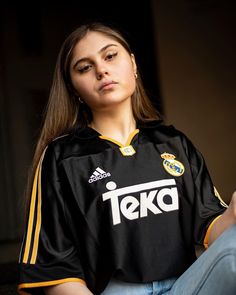 a woman sitting on the ground with her eyes closed wearing a jersey that says teka