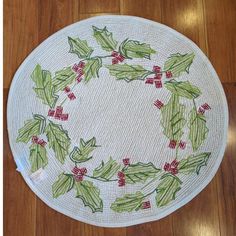 a round rug with holly and red berries on the bottom is sitting on a wooden floor