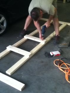 a man is working on some kind of platform in the garage with an electric drill