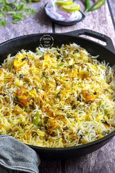 a pan filled with rice and vegetables on top of a wooden table