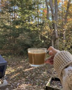 a person holding a cup of coffee in front of a camper's grill