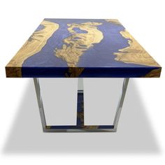 a blue table with gold leaf design on top and metal legs, against a white background