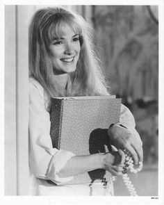 an old photo of a woman holding a book in her hands and smiling at the camera