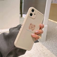 a woman holding up her phone case with a bear sticker on it