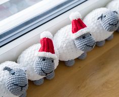 crocheted stuffed sheeps are lined up in front of a window sill