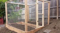 a chicken coop in the middle of a yard with dirt on the ground and fence around it